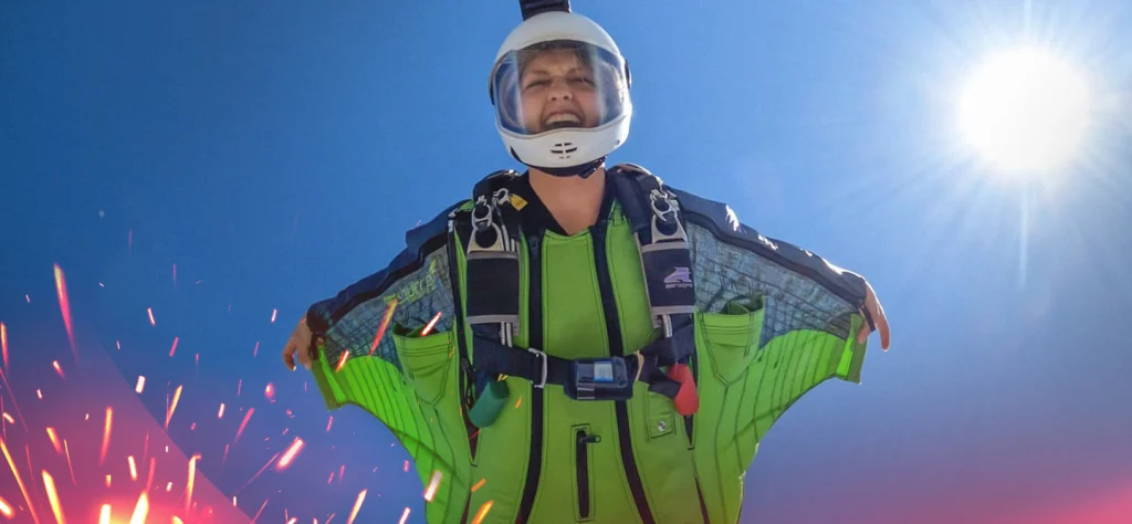 Bridget Burt in a bright green wing suit and helmet skydiving