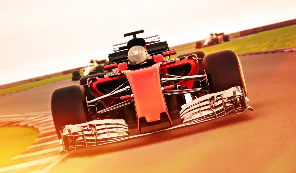 Red Formula 1 car leading a race on a sunny track, with other cars blurred in the background.