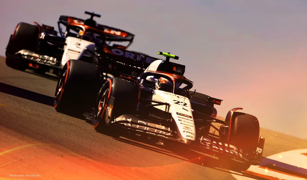 Close-up of two Formula 1 cars racing closely, showcasing team branding and intense action.