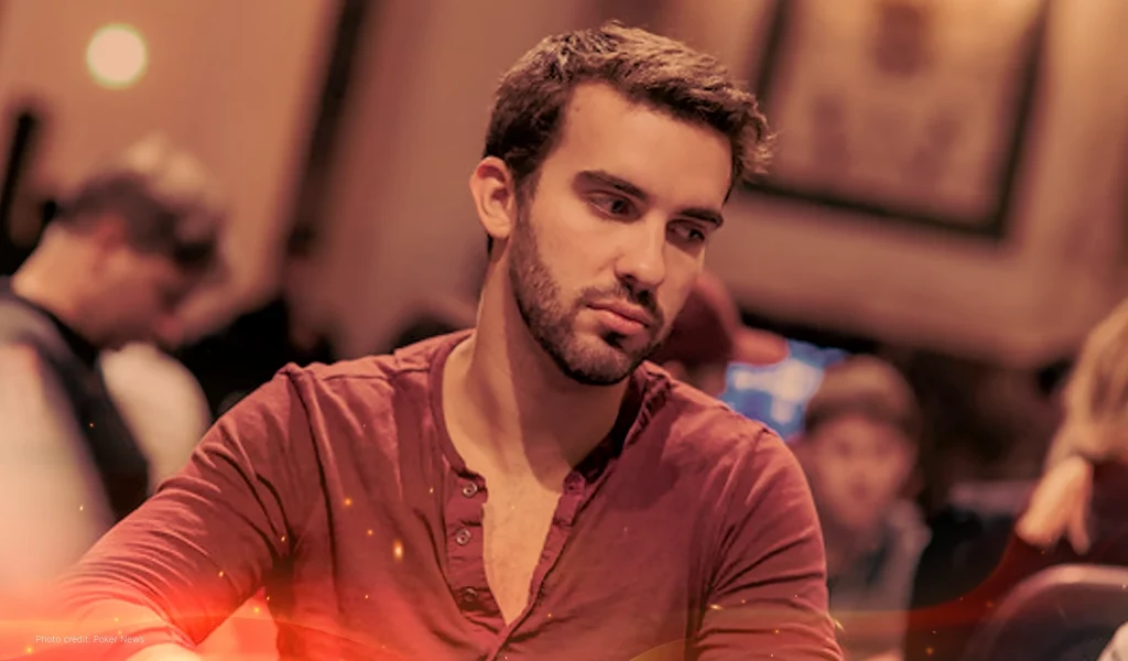 Jeff Rossiter, in a red shirt, looks intently at the poker table, surrounded by blurred players in a tournament setting.