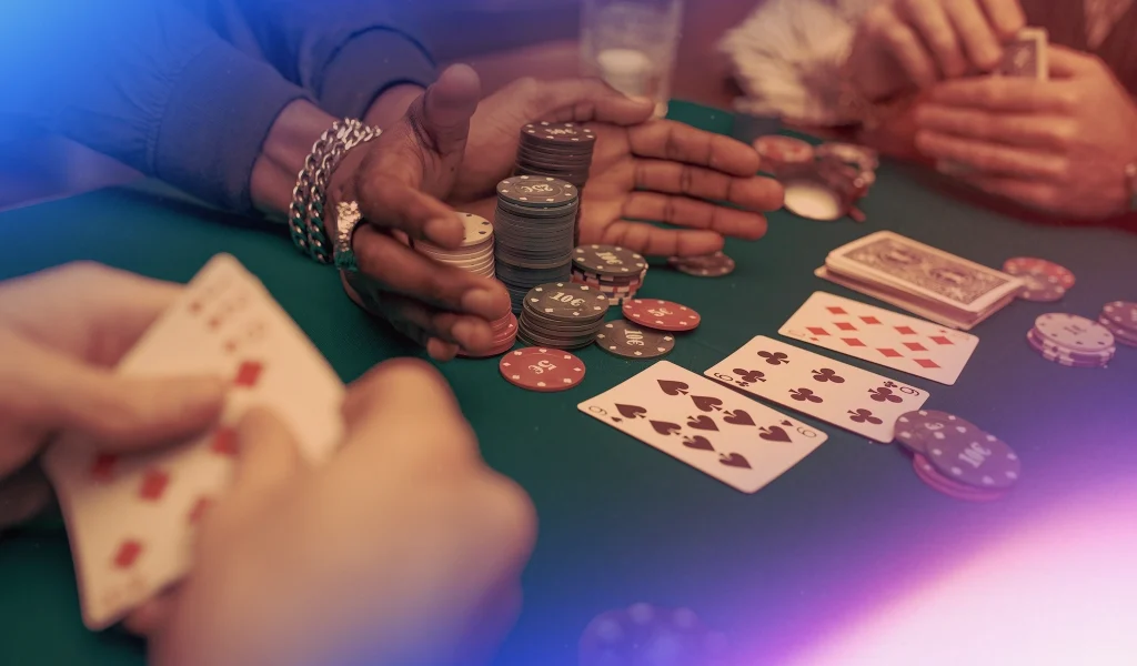 Poker hand and chips on a green table, with players reaching for their stacks after a winning hand is revealed.