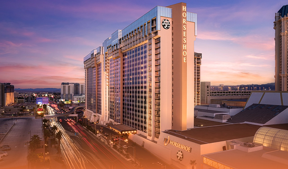 Exterior view of Horseshoe Casino in Las Vegas at sunset with the city lights on.