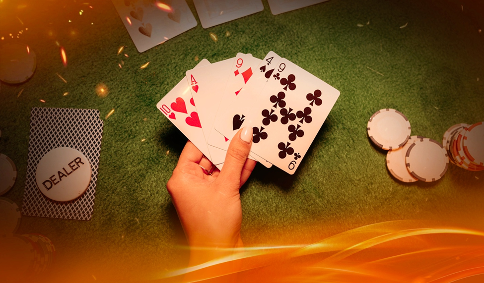 A hand holding five poker cards over a green felt table, surrounded by poker chips and a dealer button.