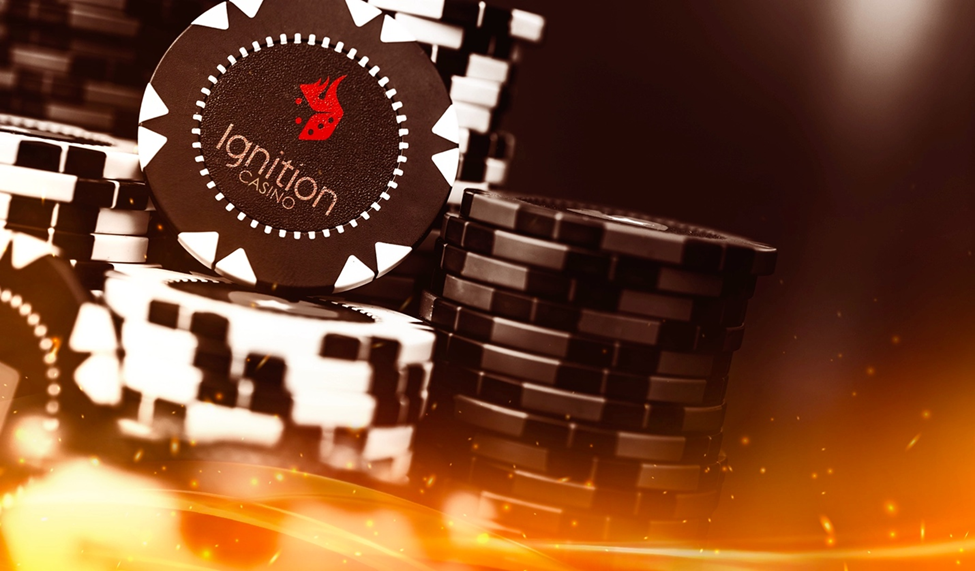 Close-up of stacked black and white Ignition Casino poker chips, illuminated by warm lighting.