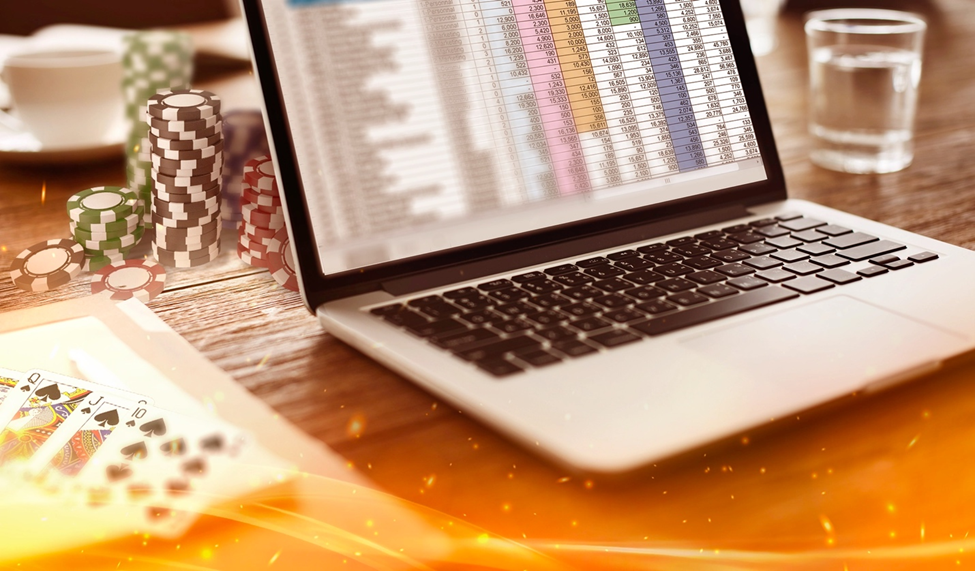 Laptop with a spreadsheet open next to poker chips and a deck of cards, symbolizing performance tracking for poker bankroll management.