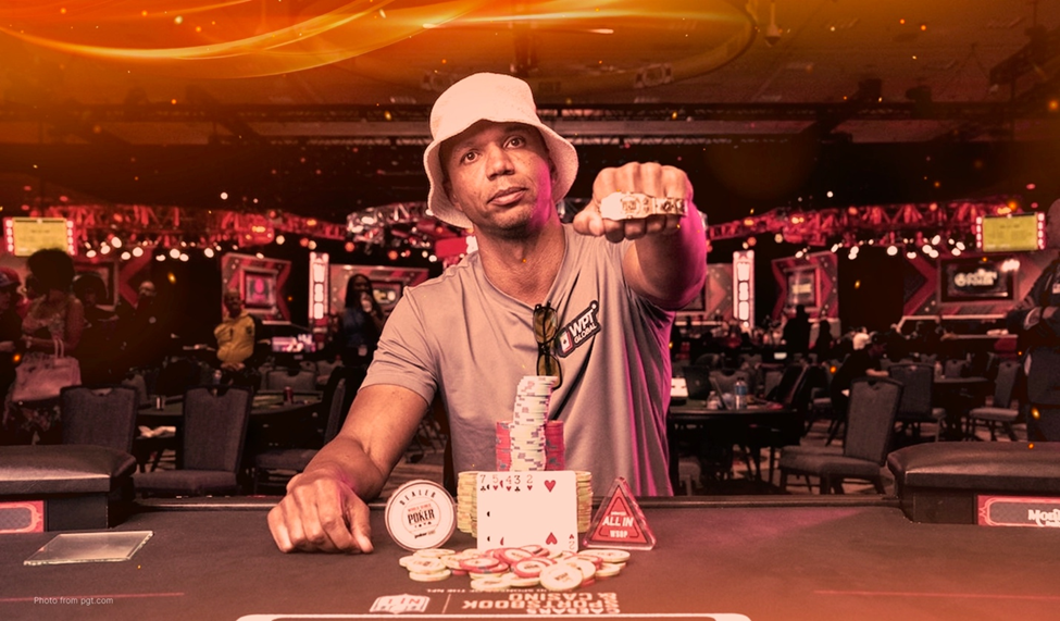 Phil Ivey at a poker table, wearing a bucket hat and WPT Global shirt, showing off a championship ring with poker chips stacked in front.